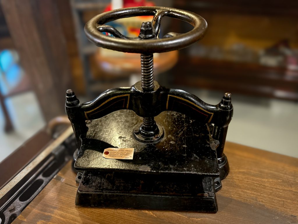 This antique cast iron book press features a bold industrial design with a functional screw mechanism—perfect for bookbinding, display, or decor.